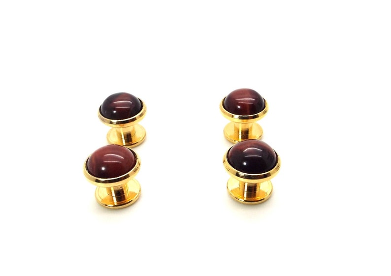 May include: Set of four gold cufflinks with red tiger's eye stone insets.
