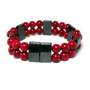 May include: A double-strand bracelet with red beads and black rectangular magnetic clasps.