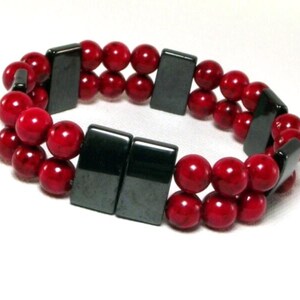 May include: A double-strand bracelet with red beads and black rectangular magnetic clasps.