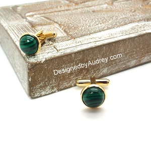 May include: Gold cufflinks with green malachite stone insets. The cufflinks are on a wooden surface with the text "DesignedbyAudrey.com".