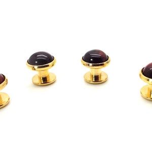 May include: Set of four gold cufflinks with red and black gemstone tops.