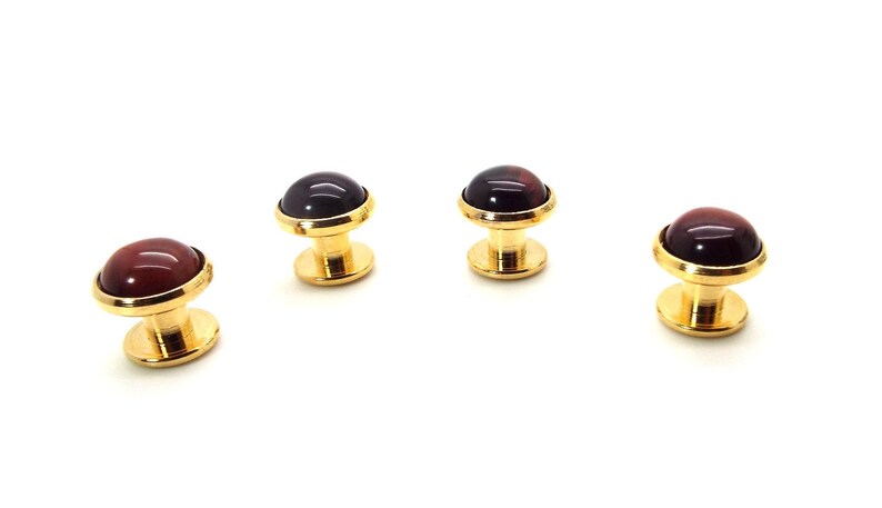 May include: Set of four gold cufflinks with red and black gemstone tops.