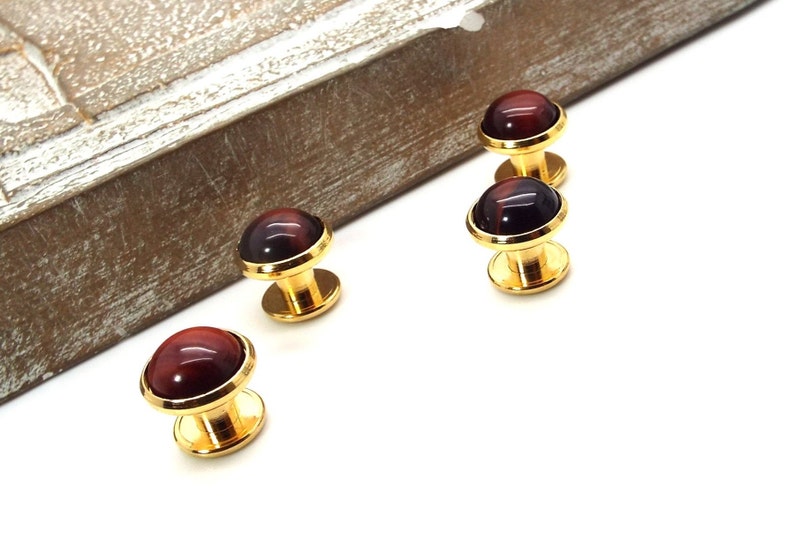 May include: Set of four gold cufflinks with red tiger's eye stone inlays.