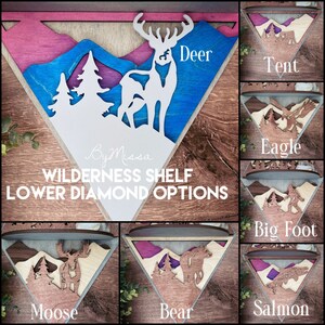 May include: A set of six wooden triangle shelves with different wildlife designs. The shelves are painted in various colors, including blue, pink, and brown. The designs include a deer, a tent, an eagle, a bigfoot, a moose, and a salmon. The text "By Missa WILDERNESS SHELF LOWER DIAMOND OPTIONS" is printed on the top shelf.