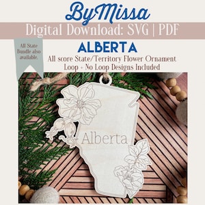 May include: A wooden ornament shaped like the province of Alberta, Canada, with a floral design and the word "Alberta" written on it. The ornament is designed for crafting and can be used as a Christmas ornament or a home decor piece.