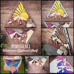 May include: A wooden diamond-shaped shelf with a mountain scene and a deer silhouette. The shelf has two levels and is painted in shades of brown, yellow, and purple. The text "BYMISSA.NET Wilderness Diamond Shelf" is printed on the bottom of the shelf.