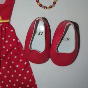 Puede incluir: Un vestido rojo con lunares blancos, zapatos rojos y una pulsera de cuentas. El vestido tiene lunares blancos y un ribete amarillo. Los zapatos rojos tienen las letras "AFW" impresas en el interior. La pulsera tiene cuentas rojas, amarillas y blancas.
