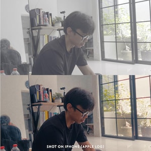 May include: A person wearing a black shirt and glasses, working indoors. The image is taken in natural light, with a window and plants visible in the background. The text "SHOT ON IPHONE (APPLE LOG)" is at the bottom.
