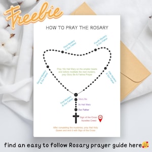 May include: A white card with the text "HOW TO PRAY THE ROSARY" and a diagram of a rosary. The diagram includes text explaining the steps of the prayer. The words "Freebie" and "find an easy to follow Rosary prayer guide here" are also present.