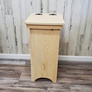May include: A wooden bin with two openings on the top. The bin is made of natural wood and has a simple design.