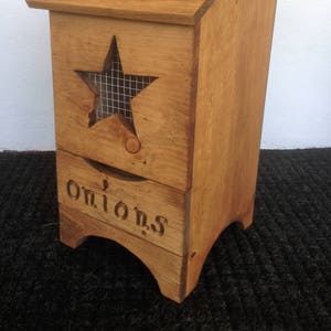 May include: A wooden storage bin with a star-shaped cutout and a drawer. The bin is labeled "Taters" on the top and "Onions" on the drawer.