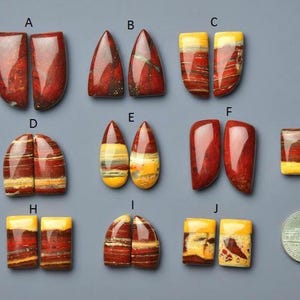 Puede incluir: Una colección de diez pares de piedras preciosas pulidas de varias formas y colores, incluyendo rojo, amarillo y marrón. Las piedras preciosas se muestran sobre una superficie gris, con una moneda de cuarto de dólar estadounidense para comparar el tamaño.