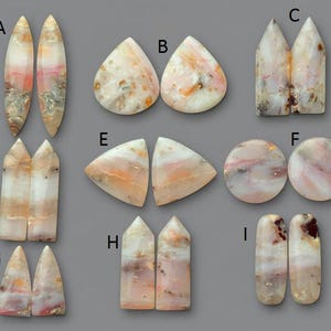 Puede incluir: Una colección de nueve pares de piedras preciosas pulidas en varias formas, incluyendo lágrima, ovalada y triangular. Las piedras presentan una mezcla de colores, incluyendo blanco, rosa y naranja, con algunas inclusiones más oscuras. El fondo es gris sólido.