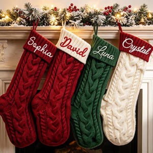 May include: Four cable-knit Christmas stockings hanging in a row. The first is red with a white cuff embroidered with 'Sophia'. The second is red with a white cuff embroidered with 'David'. The third is green with 'Luna' embroidered on the cuff.