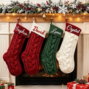 May include: Four cable-knit Christmas stockings hanging in a row. Two are red with white cuffs, one is green with a green cuff, and one is white with a red cuff. Each stocking features embroidered names: Sophia, David, Luna, and Crystal in white or red script.