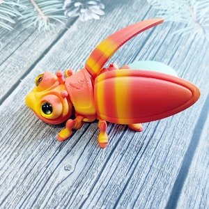 May include: A colorful, 3D-printed insect toy with a vibrant design. The toy features a combination of orange, yellow, and red hues, with large, expressive eyes. The insect has articulated wings and legs, giving it a playful appearance.