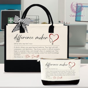 May include: A canvas tote bag and matching cosmetic bag set. The bags are white with black accents and feature the text "difference maker" with a heart and stethoscope design. A black and white striped bow adorns the tote bag.