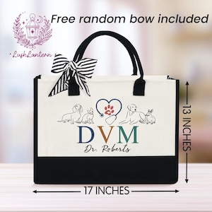 May include: A white canvas tote bag with black trim and handles. The bag features a design of a stethoscope, a heart with a paw print, and various animals including a dog, a cat, and a rabbit. The text "DVM Dr. Roberts" is printed on the bag. The bag measures 17 inches wide and 13 inches tall.