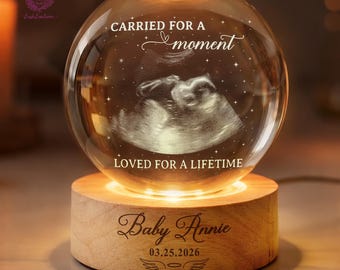 May include: A glowing crystal ball lamp with a wooden base. The crystal ball displays an ultrasound image and the text "CARRIED FOR A moment LOVED FOR A LIFETIME." The wooden base is engraved with the name "Baby Annie" and the date "03.25.2026".