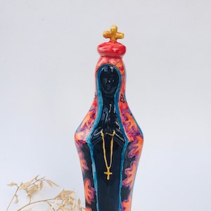 Peça cerâmica da Nossa Senhora da Aparecida, rezando, cuidadosamente pintada à mão e cheia de detalhe, numa abordagem contemporânea e única