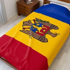 May include: A bedspread displaying the flag of Moldova. The design features a yellow field with a coat of arms, a blue stripe at the top, and a red stripe at the bottom. The bedspread is on a wooden bed frame.