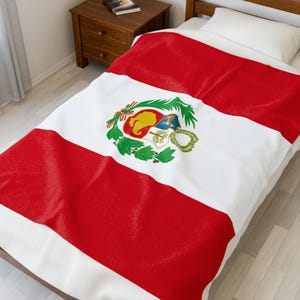 May include: A red, white, and green Peruvian flag design covers a bedspread. The flag's emblem is centered on the white stripe. The bed is made up with a white pillow and a wooden nightstand is visible in the background.