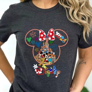 May include: Dark gray t-shirt featuring a colorful Disney design. The design includes a castle, Mickey and Minnie Mouse, and other characters. The word "Disney" is written in rainbow colors. A red and white polka dot bow is at the top.