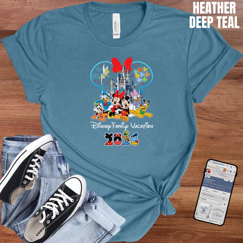 May include: A heather deep teal t-shirt featuring a Disney Family Vacation design with Mickey and Minnie Mouse, Donald Duck, and other characters. The design includes a castle and the year 2023.