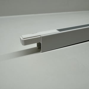 May include: White plastic cable cover with a gray insert. The cover is designed to conceal and protect electrical wires.