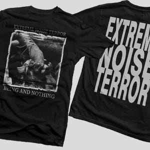 Peut inclure: T-shirts noirs avec le nom du groupe "EXTREME NOISE TERROR" imprimé en blanc. Le devant du t-shirt présente une image en noir et blanc avec le texte "BEING AND NOTHING". Le dos du t-shirt porte le nom du groupe en grandes lettres blanches.