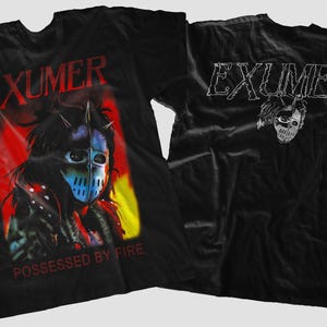 May include: Black t-shirt with the band name "EXUMER" in red and a masked figure against a fiery backdrop. The reverse side shows the band name in white and a skull graphic. The text "POSSESSED BY FIRE" is also visible on the front.