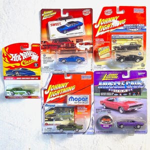 May include: A collection of five die-cast toy cars in their original blister packaging. The set includes a green Hot Wheels Dodge Challenger Funny Car, and four Johnny Lightning models: a blue Dodge Challenger, a black Dodge Challenger, a green Mopar Dodge Challenger, and a purple Dodge Challenger.