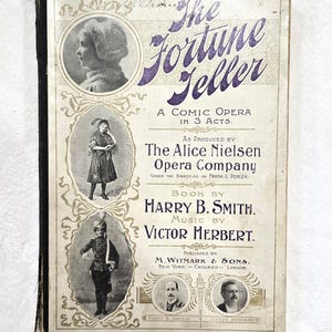 May include: A vintage vocal score book titled The Fortune Teller, a comic opera in 3 acts. The cover features purple text, black and white portraits of Alice Nielsen, Harry B. Smith, and Victor Herbert, and illustrations of performers in costume.