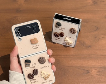 May include: A light beige phone case with a flip design, featuring a bear and coffee-themed decorations. The case includes a coffee cup, coffee beans, cookies, and the text "Lovely Bear". The phone displays the time and date.