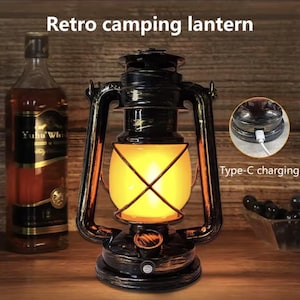 Puede incluir: Una linterna de camping retro en negro y dorado, con un brillo amarillo cálido. Tiene un puerto de carga Tipo-C. El texto "Retro camping lantern" es visible en la parte superior de la imagen.