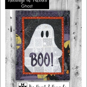 May include: A white ghost with the word "BOO!" on it. The ghost is surrounded by a black and purple fabric with a red and white polka dot border. The fabric has a Halloween theme with bats, spiders, and pumpkins.
