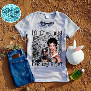 May include: A gray t-shirt with a black and white graphic print of a man with the text "It's not my first or my last".