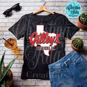 May include: Black t-shirt featuring a red and white graphic of the state of Texas with the text "Gilley's Pasadena, TX". The shirt is displayed with sunglasses, a drink, jeans, and cacti.