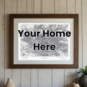 May include: A framed black and white map print with the text "Your Home Here" in a brown frame hanging on a wood wall.