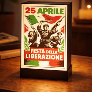 May include: A rectangular lamp with a graphic depicting figures holding flags and weapons, with the text "25 APRILE" and "FESTA DELLA LIBERAZIONE" in red and green. The lamp is on a wooden surface.