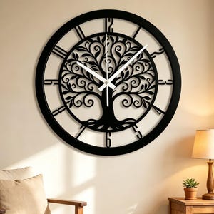 May include: A large, circular black wall clock featuring an intricate cutout design of a tree with swirling branches in the center. The clock has white hour and minute hands and black numerals positioned around the outer edge of the frame.
