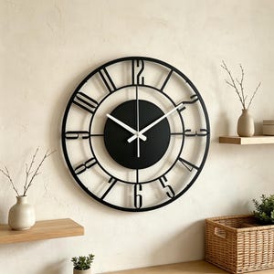 Puede incluir: Un gran reloj de pared circular con un diseño de marco abierto en color negro y números recortados prominentes. El centro consiste en una placa circular negra sólida con manecillas blancas finas para horas, minutos y segundos.