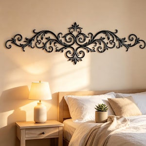 May include: A black wall-mounted decorative piece featuring an intricate, symmetrical scrollwork design with swirling patterns and leaf-like motifs. The horizontal ornament is centered above a bed, showcasing a detailed, ornate metal-like structure.