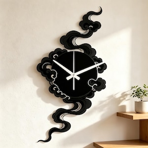 May include: A black wall clock featuring a circular face surrounded by stylized, flowing black cloud motifs that extend vertically above and below the center. The clock has three thin, white hands positioned against the solid black circular background.