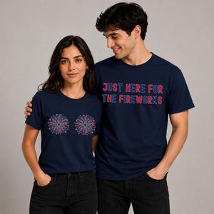 A man and a woman wearing matching navy blue t-shirts with the text "Just here for the fireworks" and a graphic of fireworks.