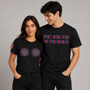 A man and a woman standing next to each other, both wearing black t-shirts with a design of fireworks on them.