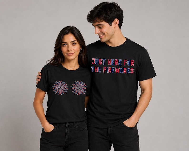 A man and a woman standing next to each other, both wearing black t-shirts with a design of fireworks on them.