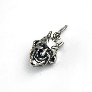 May include: Silver charm pendant featuring a detailed, grinning, grotesque face with horns.