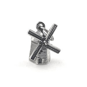 May include: Silver charm in the shape of a windmill. The charm is detailed with a small building and a windmill blade.