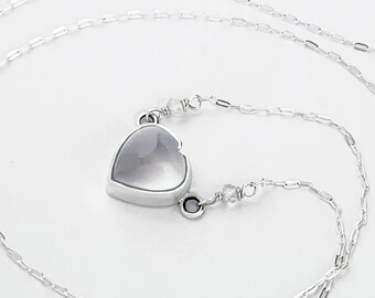 May include: A silver chain necklace with a heart-shaped pendant featuring a clear crystal. The chain is a delicate box chain with a lobster clasp.